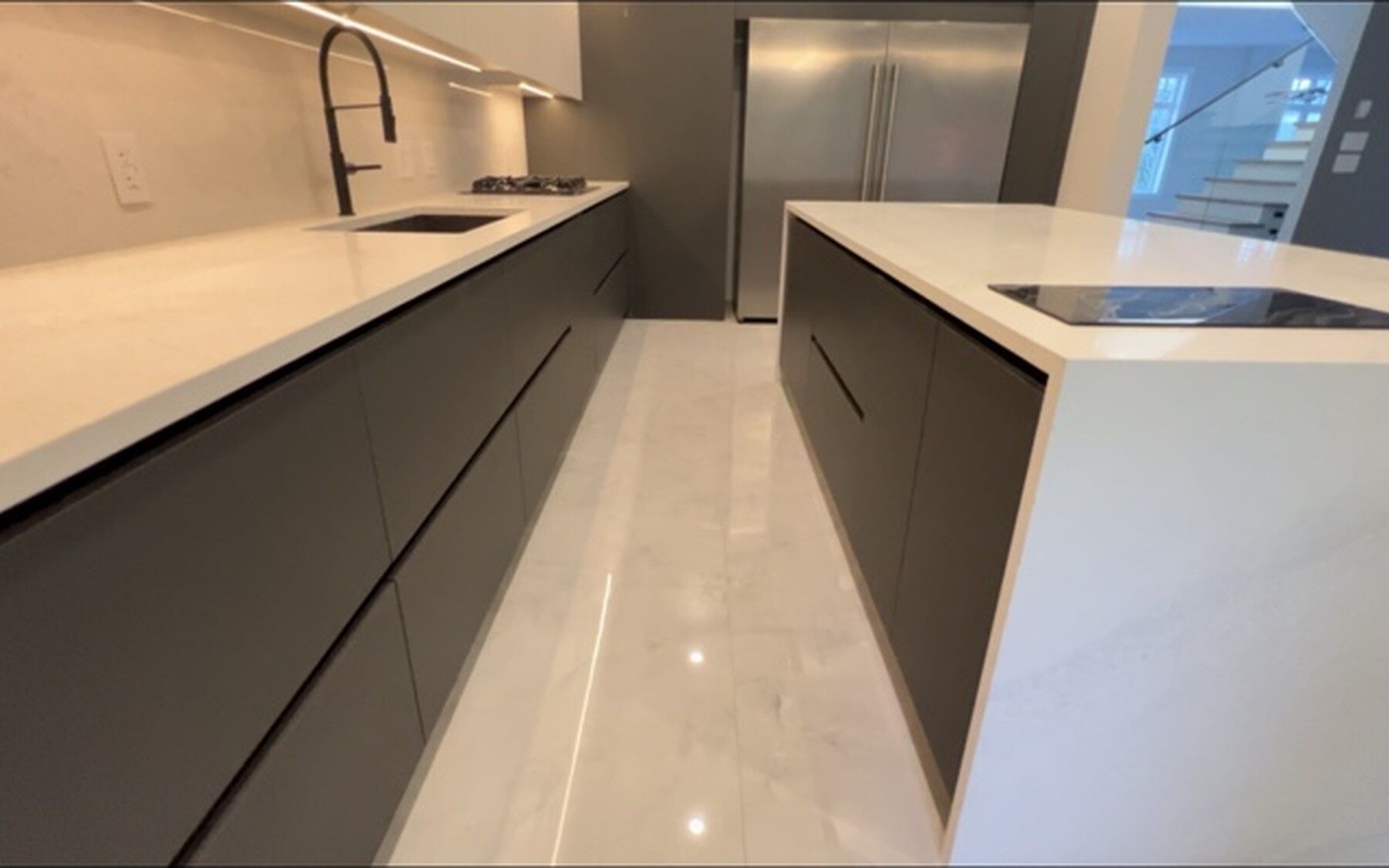 Finished Capilano kitchen looking down the dark cabinetry run toward the integrated refrigerator