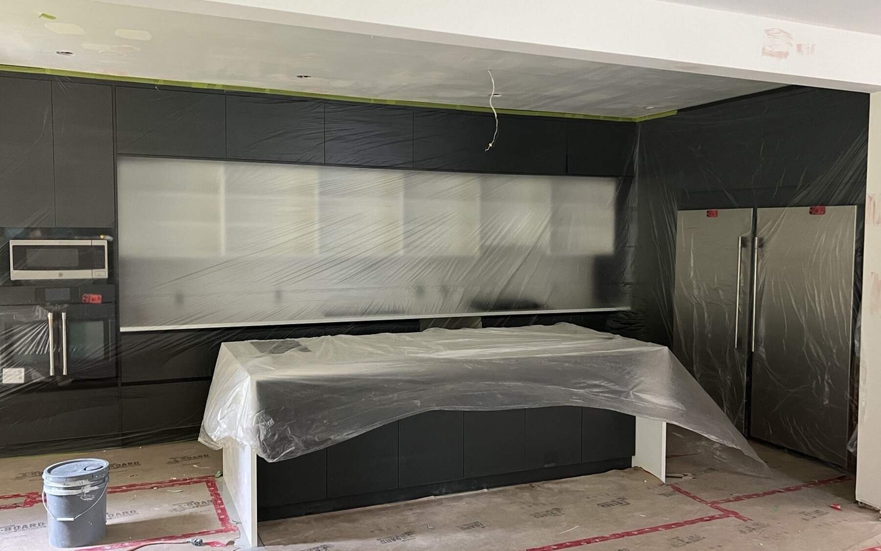 The finished cabinetry wrapped in protective sheeting while flooring and finishing work is completed