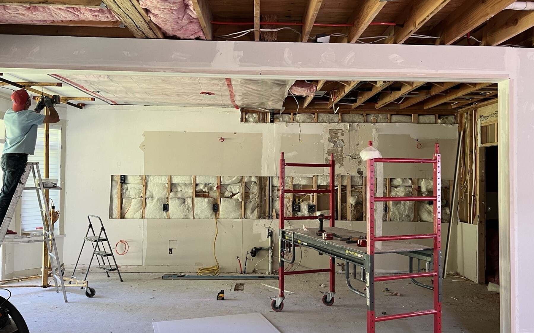 Structural opening in progress: the removed wall replaced by a beam and posts, with exposed joists and rough electrical