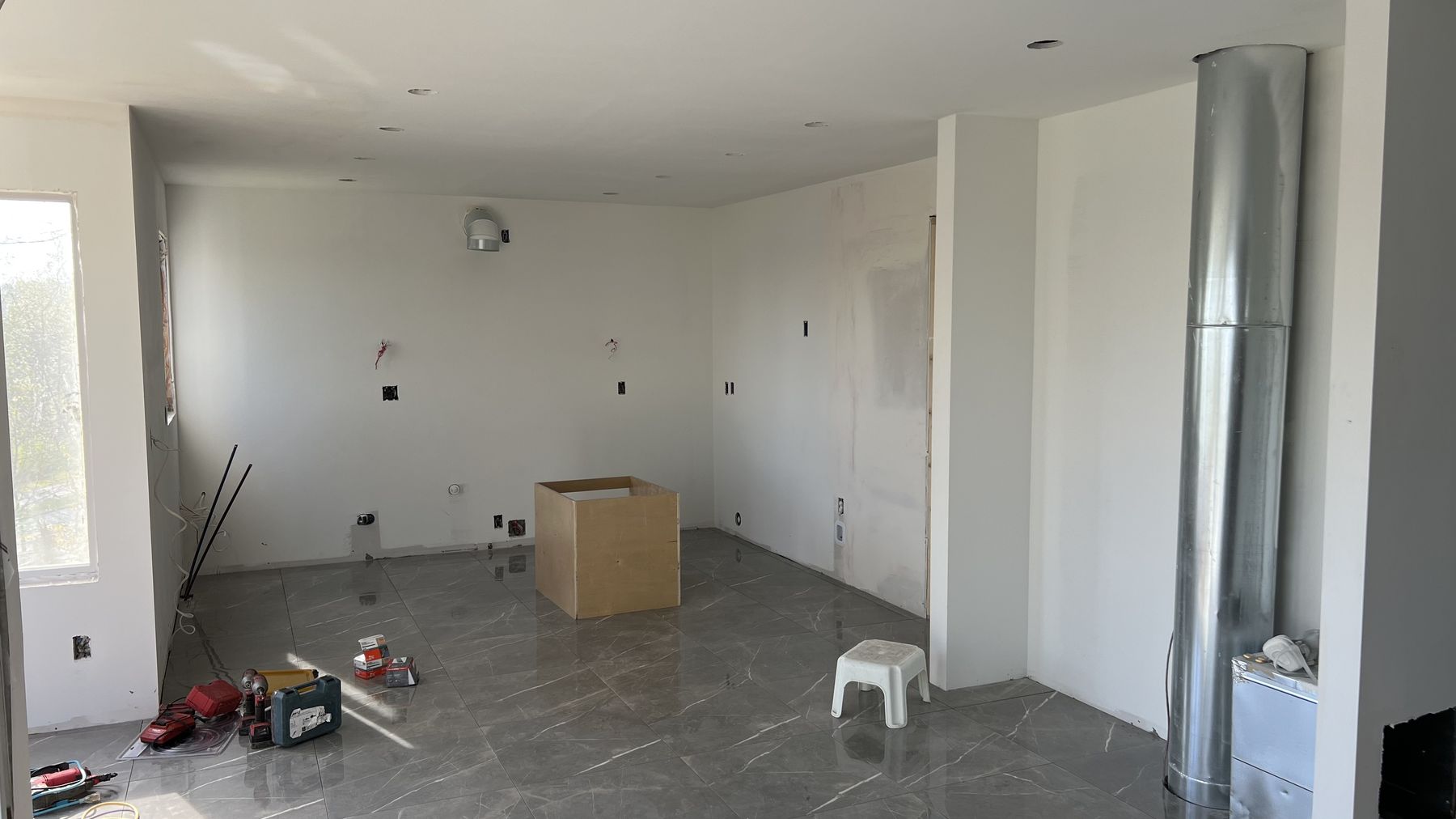The kitchen closed in and painted, with large-format marble-look porcelain flooring laid and the range duct boxed