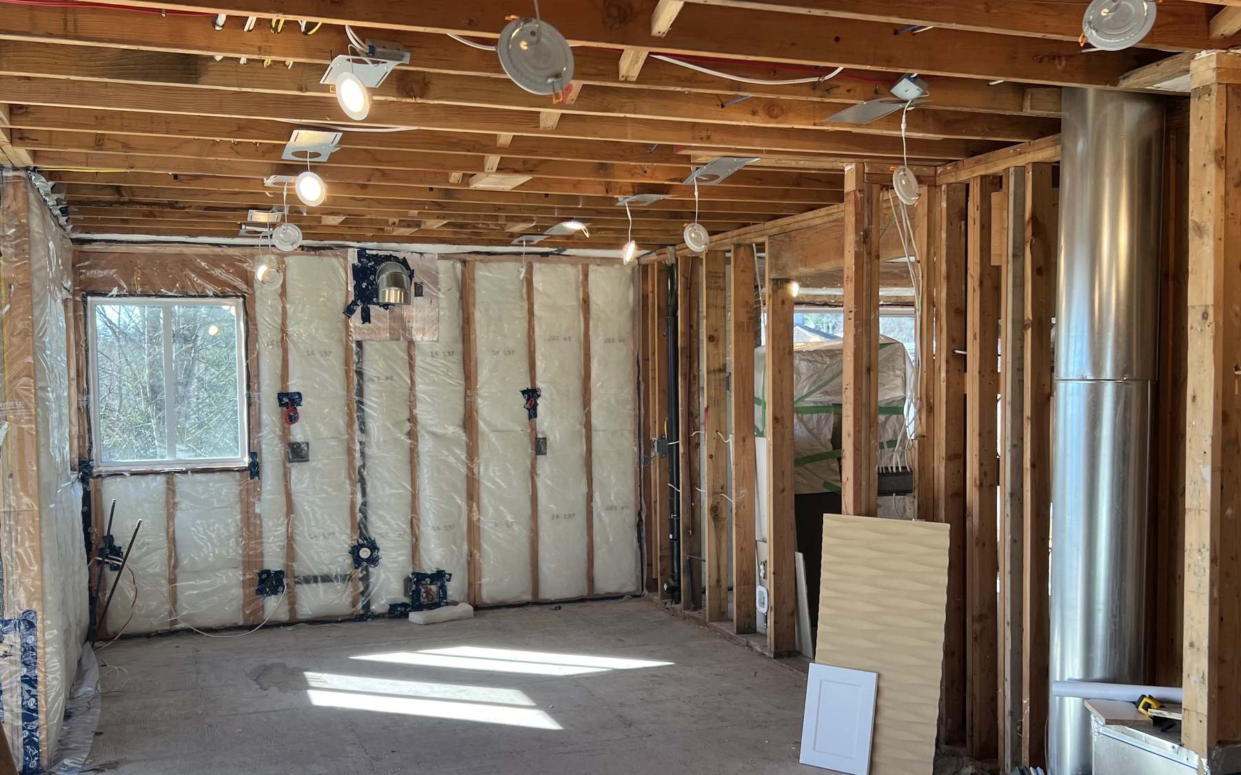 The Coquitlam kitchen stripped back to open studs and ceiling joists, with insulation in and the range duct installed